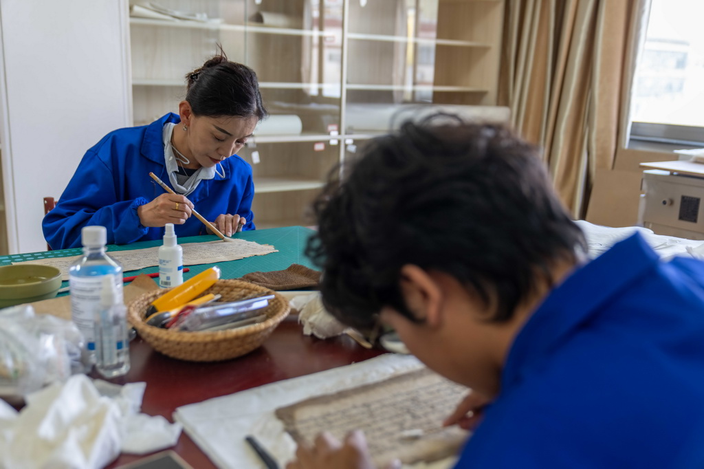 西藏自治区古籍保护中心古籍修复员次仁央宗(左)与同事对古籍进行除霉(2025年8月13日摄)。新华社记者 晋美多吉 摄 西藏自治区古籍保护中心古籍修复员次仁央宗(左)与同事对古籍进行除霉(2025年8月13日摄)。新华社记者 晋美多吉 摄